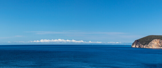Panorama view on vivid blue sea with scenic sky and cliffs, sunny sea shore on a bright clear day in Greece. Scenic travel destination. Lefkada island, Ionian sea coast