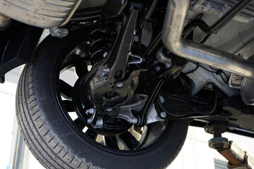 Modern powerful car on a lift in a car service. Rear suspension structure and elements. Selected...