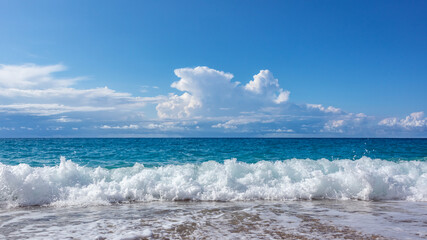 Scenic sunny pebble beach with blue stormy waves and white foam. Epic cloudscape on shoreline of Lefkada island in Greece. Summer nature vacation travel to Ionian Sea