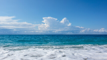 Obraz premium Scenic blue stormy waves and white foam with epic cloudscape on coast of Lefkada island in Greece. Summer nature vacation travel to Ionian Sea