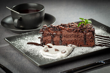 A piece of chocolate cake with mint on the table, served with fruit tea
