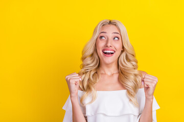 Photo of young cheerful woman happy positive smile rejoice victory success look empty space isolated over yellow color background