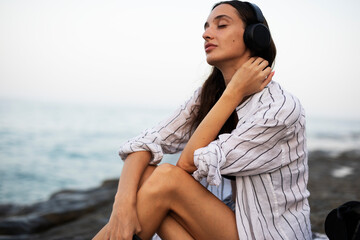 Hot woman relaxing on the sandy beach. Beautiful woman with headphones listening the music.