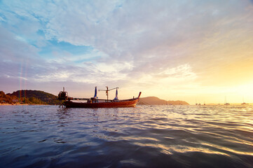 Travel in Thailand.  Colorful landscape with sea beach, traditional longtail boat over beautiful sunset background.