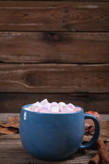 White and pink marshmallows in hot chocolate drink with copy space wooden background