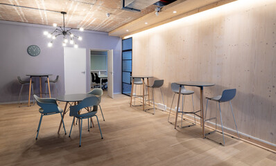 Empty chairs arranged around tables on hardwood floor in illuminated office