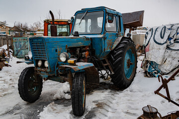 An old, rusted tractor, in the farmer's yard. Equipment for working in the field, where farmers work.