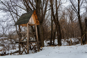 An improvised observation post, against the background of nature. A small wooden tower, made of boards and branches, among the snows, in the steppes of Russia.