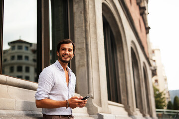 Young stylish man using the phone outdoors. Fashion happy man enjoy outdoors..