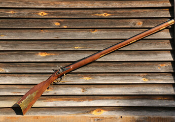 Kentucky black powder rifle on the background of an old wall of boards.