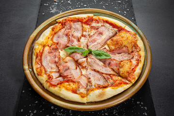 Italian bacon pizza with cheese sauce and crispy pepper with roasted spice mix, wooden dish plate on a stone table top.