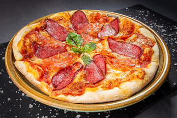 Italian salami pizza with cheese sauce and crispy pepper with roasted spice mix, wooden dish plate on a stone table top.