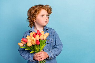 Photo portrait curly little boy looking blank space keeping tulips bouquet isolated pastel blue color background