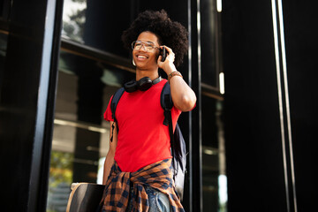 Portrait of happy african-american man with skateboard. Young fashion man using the phone.