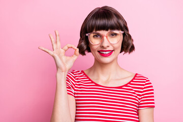 Obraz premium Photo portrait girl in spectacles smiling showing okay sign isolated pastel pink color background