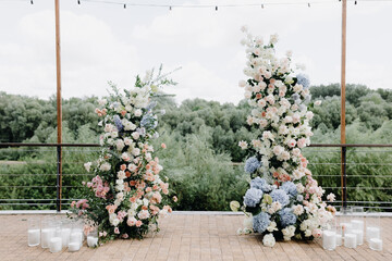 A beautiful wedding arch, decorated with flowers and greenery, near a lake or river in the open air. Decorations for an outdoor wedding ceremony