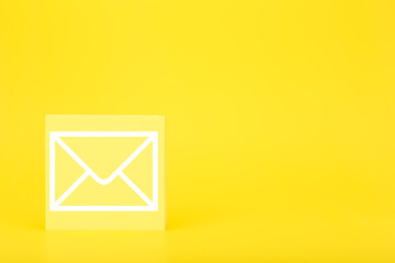 Email marketing or newsletter concept. Envelope drawn on toy square against bright yellow background with copy space