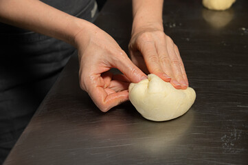 Close-up baker making bread, female hands, kneading dough, cooking