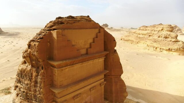 Aerial Descending To A Woman Standing In Front Of An Ancient Tomb Carved Into The Side Of A Desert Rock Formation - Arabian Desert, Saudi Arabia