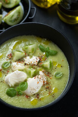 Close-up of gazpacho soup made of green tomatoes and served with mozzarella in a black bowl, vertical shot, elevated view