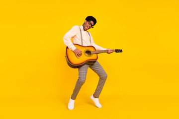 Photo of dancer guy play guitar stand tiptoe wear specs suspenders shirt isolated yellow color...