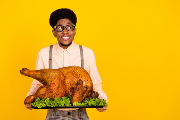 Photo of cheerful guy hold dish baked turkey look empty space wear specs suspenders shirt isolated...