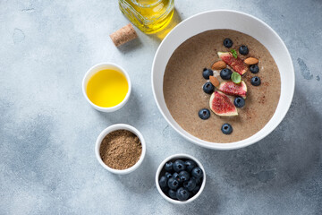 White bowl with flaxseed porridge over light-blue stone background, high angle view, horizontal shot with space