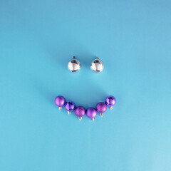 baubles making happy face.Christmas preparation idea.vivid violet and iced silver ornaments on a blue background