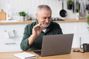 Senior caucasian man using laptop for video call sitting at home