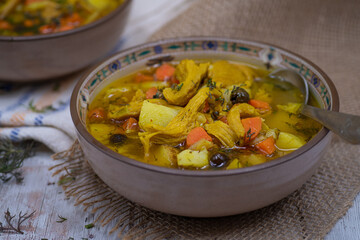 Vegan  carrot and potato soup made with seitan and vegetable stock. White wooden table, burlap cloth