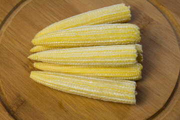 Mini corn on a wooden cutting board. Healthy vegetables. Cooking vegetarian meals. Close-up, top view.