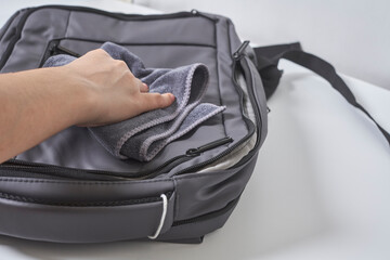 Cleaning backpack with washcloth. A person wipes off dirt or dust from the outside of the bag....