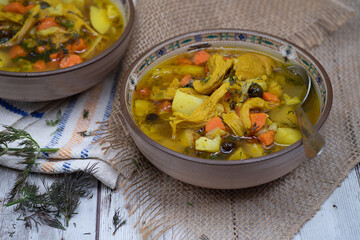 Vegan  carrot and potato soup made with seitan and vegetable stock. White wooden table, burlap cloth