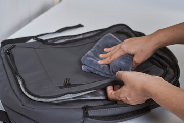 Cleaning backpack with washcloth. A person wipes off dirt or dust from the outside of the bag....