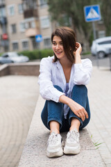 Attractive, happy and stylish brunette Caucasian girl posing on the street. Lifestyle and fashion concept.