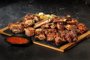 A selection of various barbecued gourmet meats on a rustic board with a black background.