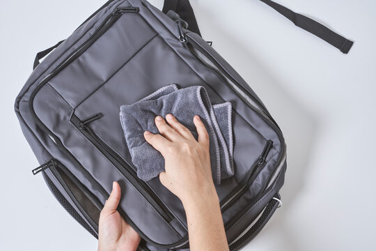 Cleaning backpack with washcloth. A person wipes off dirt or dust from the outside of the bag. Wiping school bag with damp cloth