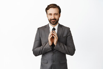 Image of corporate man smiling pleased, steeple fingers thoughtful, scheming, having interesting idea, standing in grey suit over white background