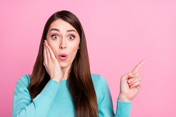 Photo of impressed funny young woman wear blue sweater arm cheek pointing finger empty space isolated pink color background