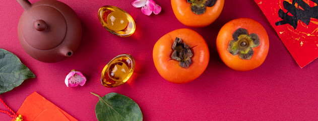 Top view of fresh sweet persimmons with leaves on red table background for Chinese lunar new year