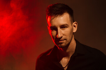 young man with smoke and red light. portrait with color combinations