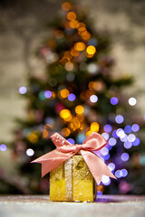 Gold Christmas gifts with pink bow, with Christmas tree bokeh lights background and copy space, Holiday, present xmas concept