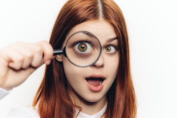 red-haired woman in a white shirt with a magnifying glass in her hands searching