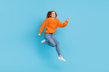 Fototapeta na wymiar Photo of pretty charming young lady dressed oversize pullover smiling jumping high isolated blue color background