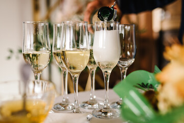 Waiter pouring Champagne in glasses on table. Party and holiday celebration concept.