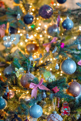 Obraz na płótnie Canvas Decorated Christmas tree close-up with sparkling baubles and bokeh christmas lights, pink bow and glitter balls, copy space