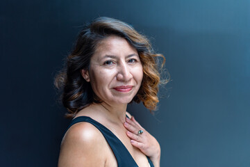 Portrait of a brunette woman in a black dress standing by a window, with deep black eyes and wavy hair © Jesus-Salas-Dual