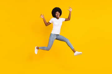 Full length photo of charming funky dark skin lady wear white t-shirt jumping high isolated yellow color background