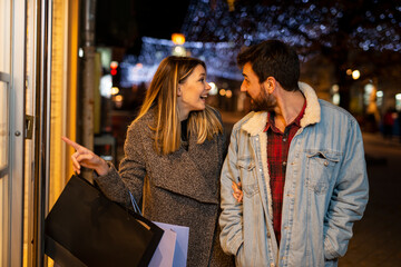 Couple window shopping outdoors in winter city street.