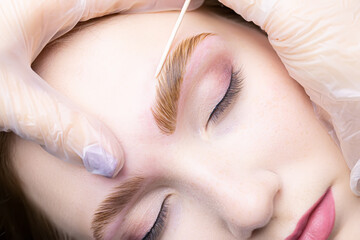 close-up alignment of the contour of the eyebrows with a cotton swab after the procedure lamination...